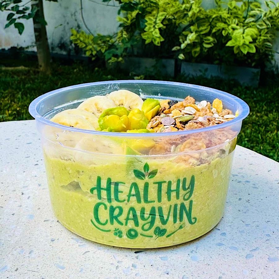 Avocado Banana bowl in a Healthy Crayvin cup, pale green base topped with banana, avocado and granola