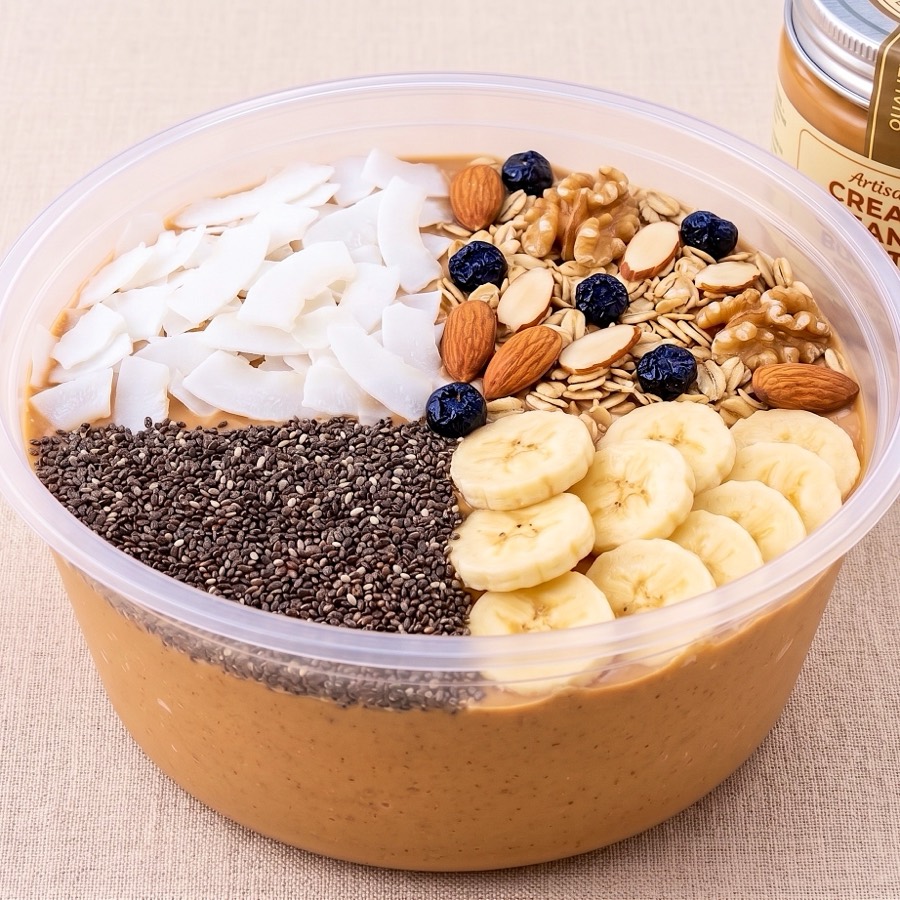 Peanut Butter Banana Protein Bowl topped with coconut flakes, oats and nuts, chia seeds and banana slices