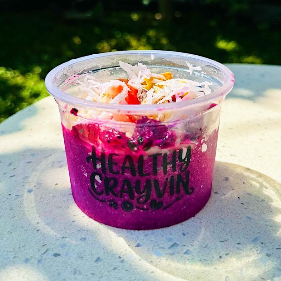Tropical Dragon Bowl Podda size in a small Healthy Crayvin cup, pink base topped with coconut, strawberry and granola