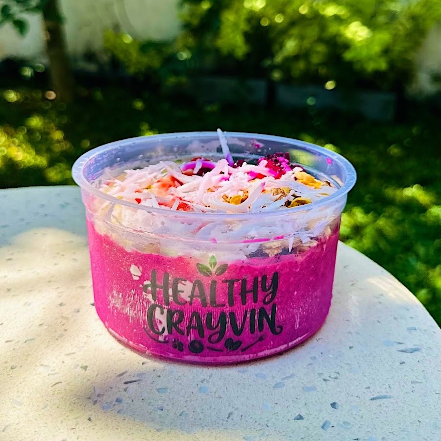 Tropical Dragon Bowl in a Healthy Crayvin cup: a bright pink dragon fruit blend topped with coconut, strawberry, dragon fruit and granola